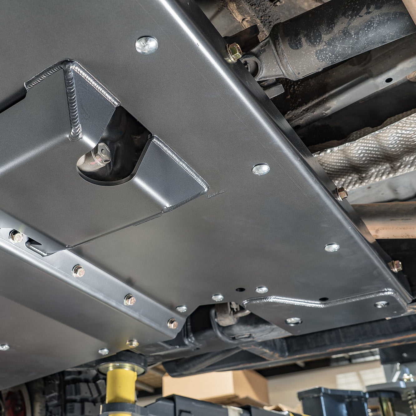 Close-up of the DRT high-clearance transmission crossmember bolted into the Tacoma frame