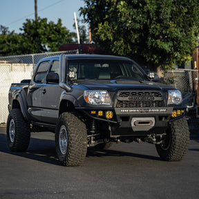Gray 2nd Gen Toyota Tacoma with DRT Hybrid Front Bumper, light bar, Baja Designs amber lights, and snorkel, lifted on street